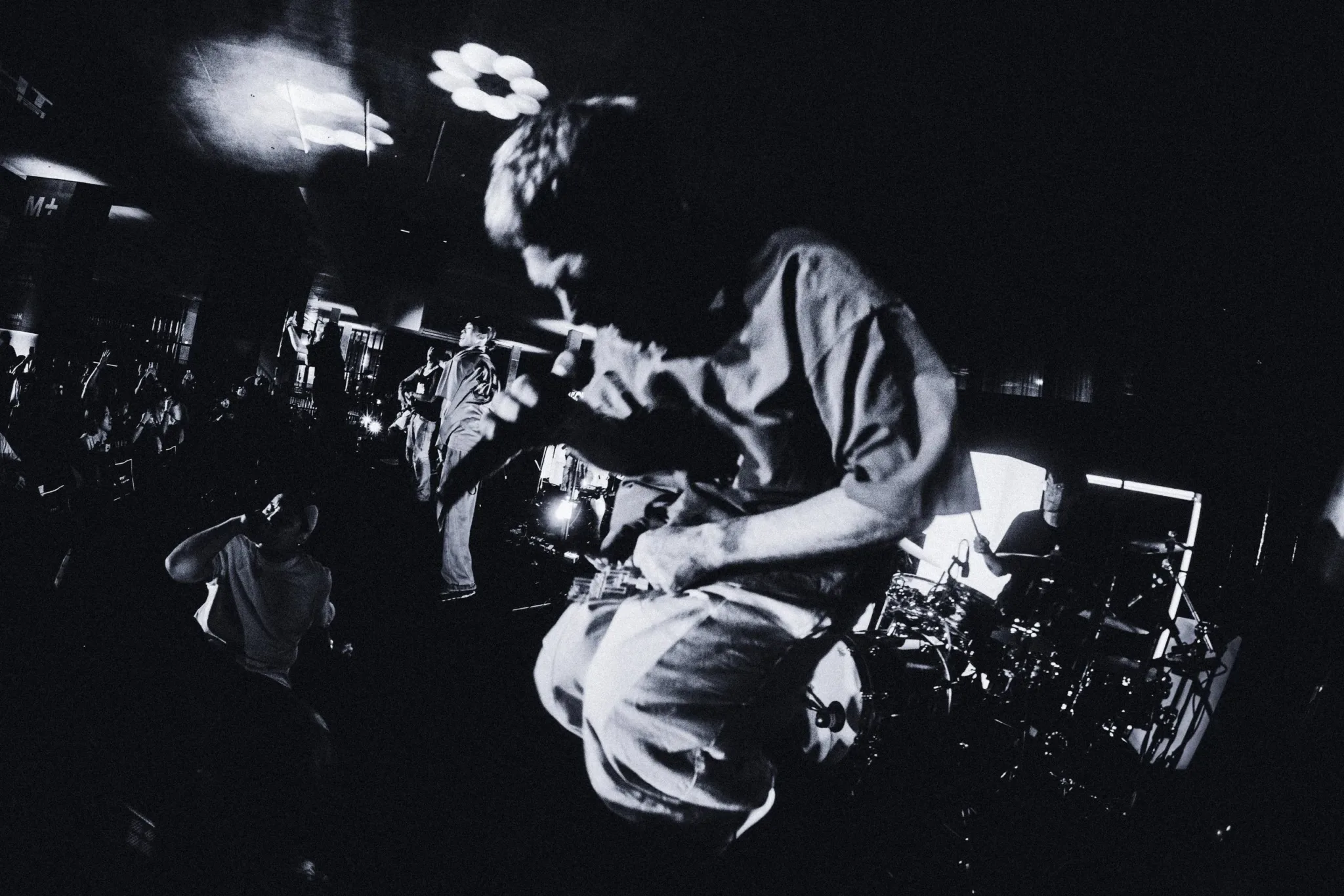 A Lazy Habits drummer mid-take behind the kit, lit by a single spotlight through the smoke