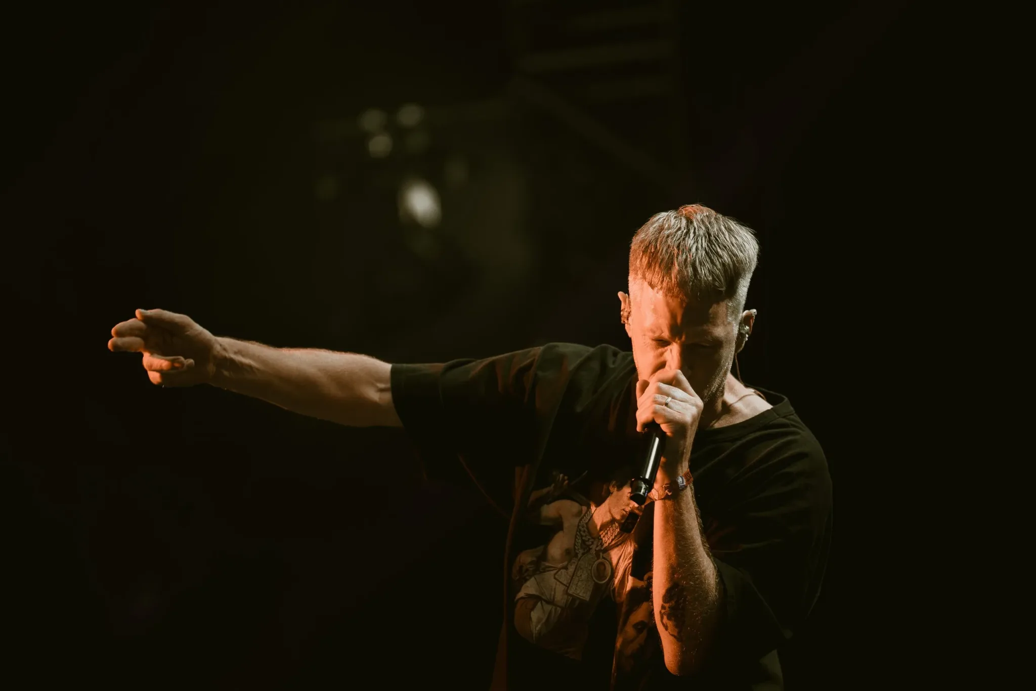 The Lazy Habits singer pointing out at the crowd under warm amber stage light